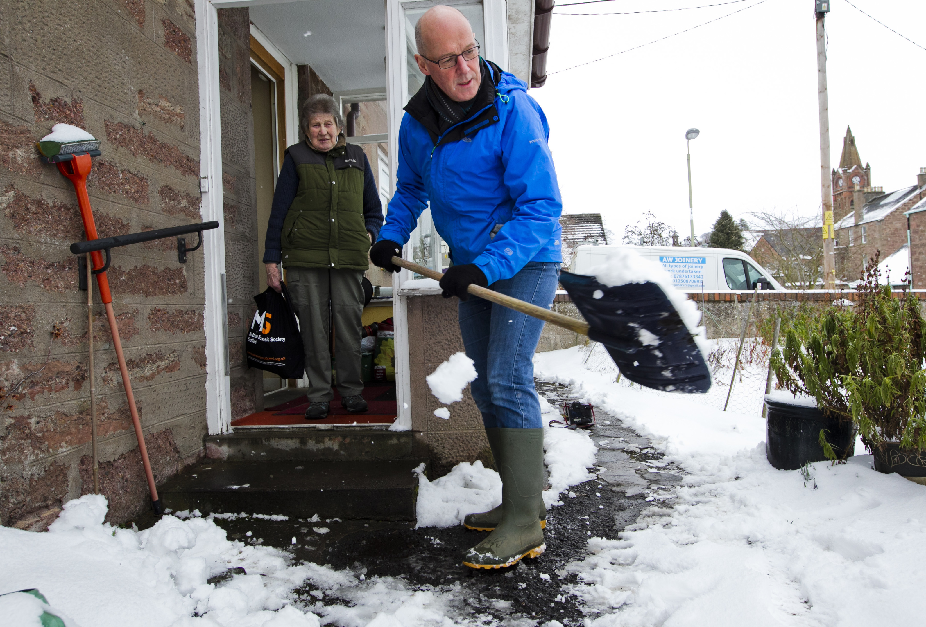 Deputy First Minister John Swinney clears the snow from Margaret Lindsay's path in Blairgowrie (Andrew Cawley / DC Thomson)