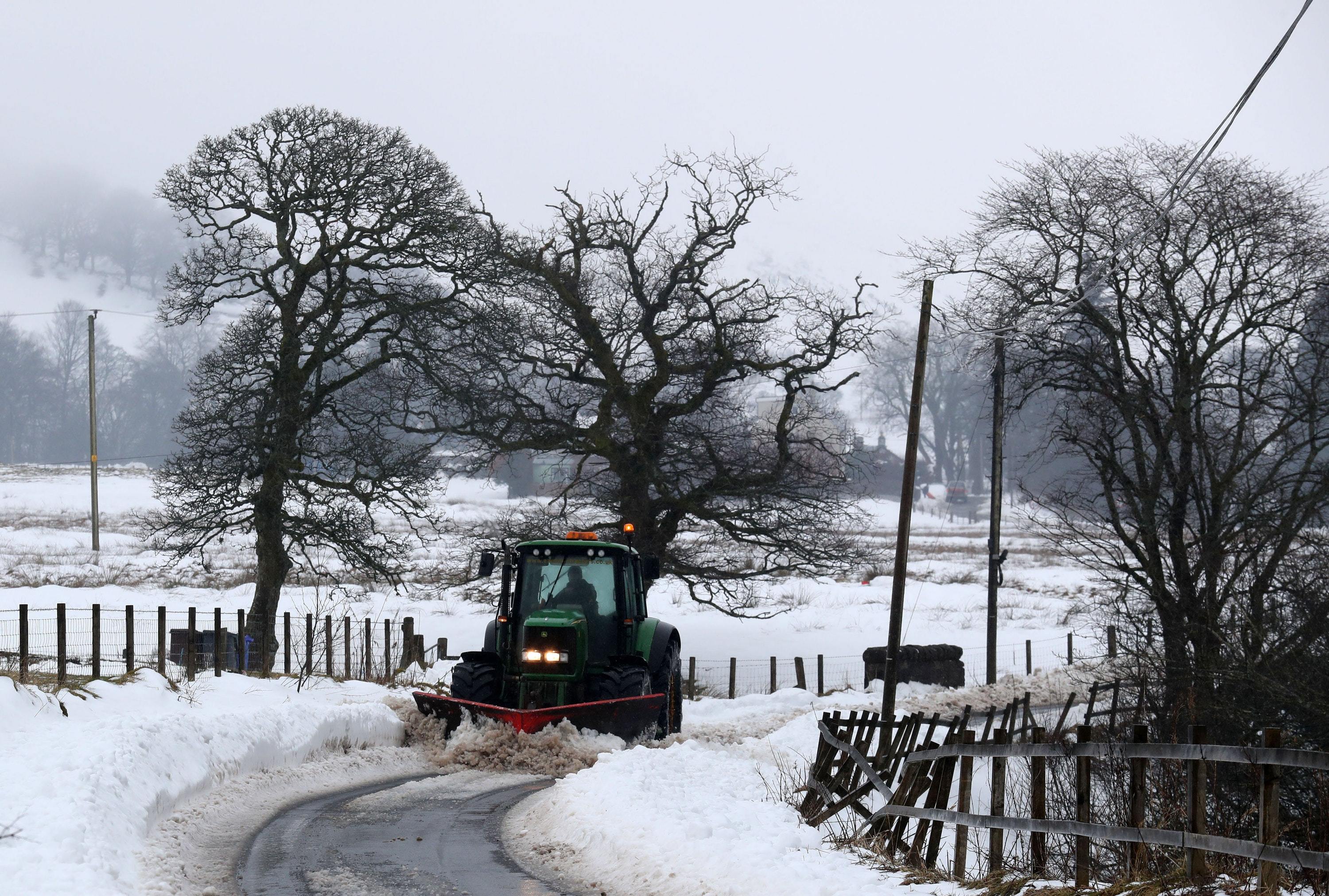 A tractor clears a rural road in the Carron Valley near Stirling, following the recent severe weather (Andrew Milligan/PA)