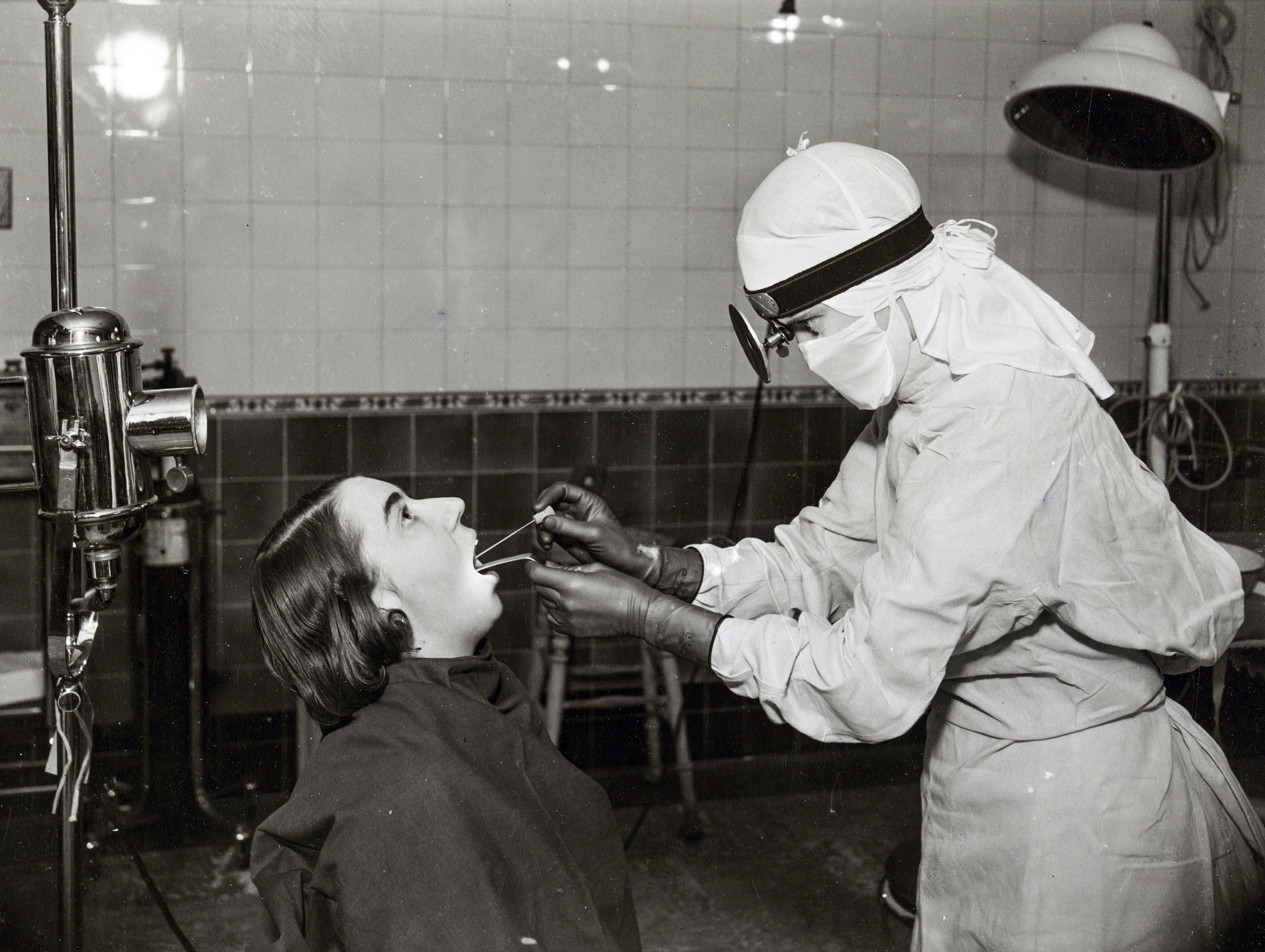 11/18/1941: A nurse in a white gown and cap taking a throat swab from a patient, at Middlesex Hospital (Historic England Archive /PA Wire)