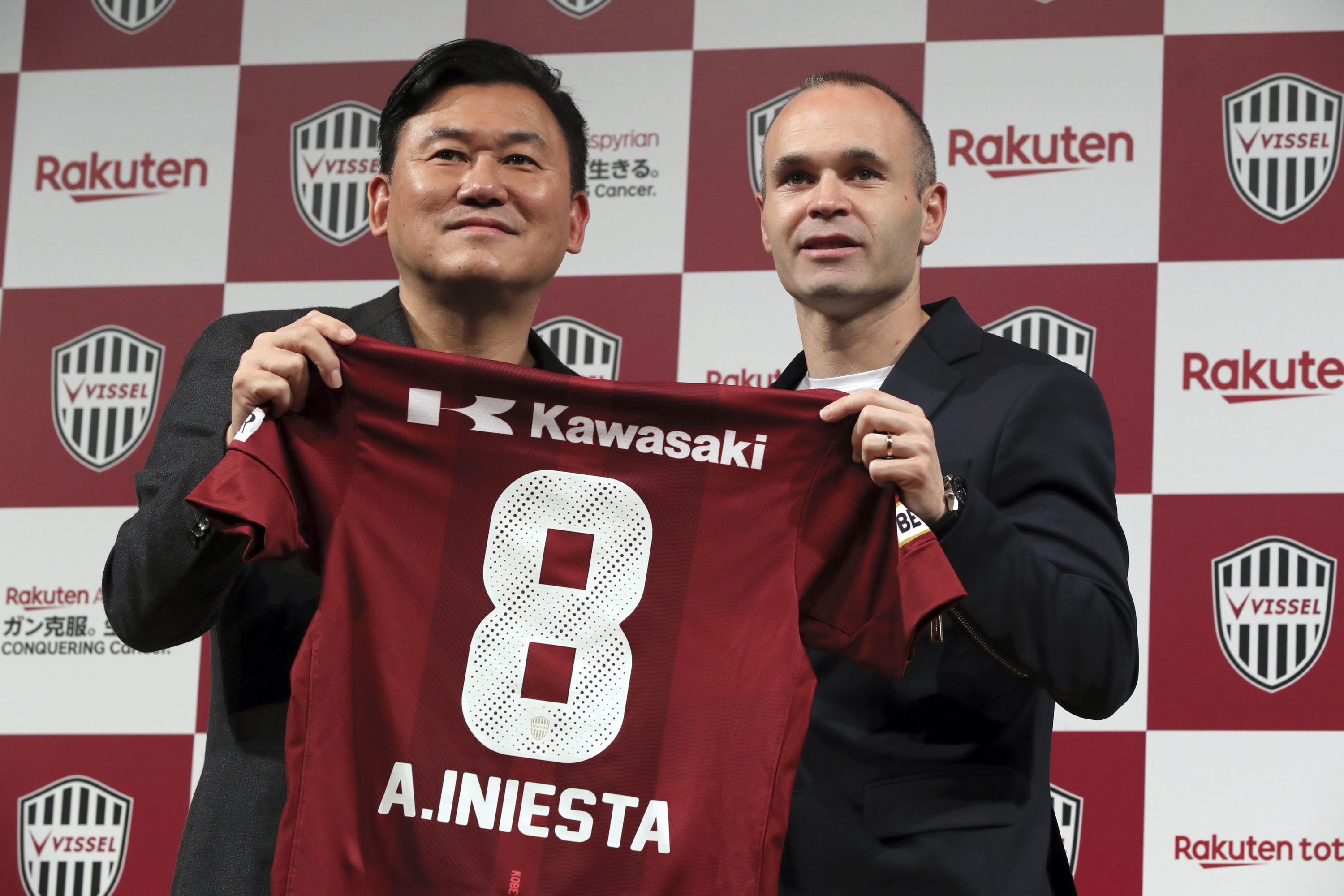 Former Barcelona player Andres Iniesta, right, holds his new shirt with Hiroshi Mikitani, left, owner of Vissel Kobe (AP Photo/Eugene Hoshiko)