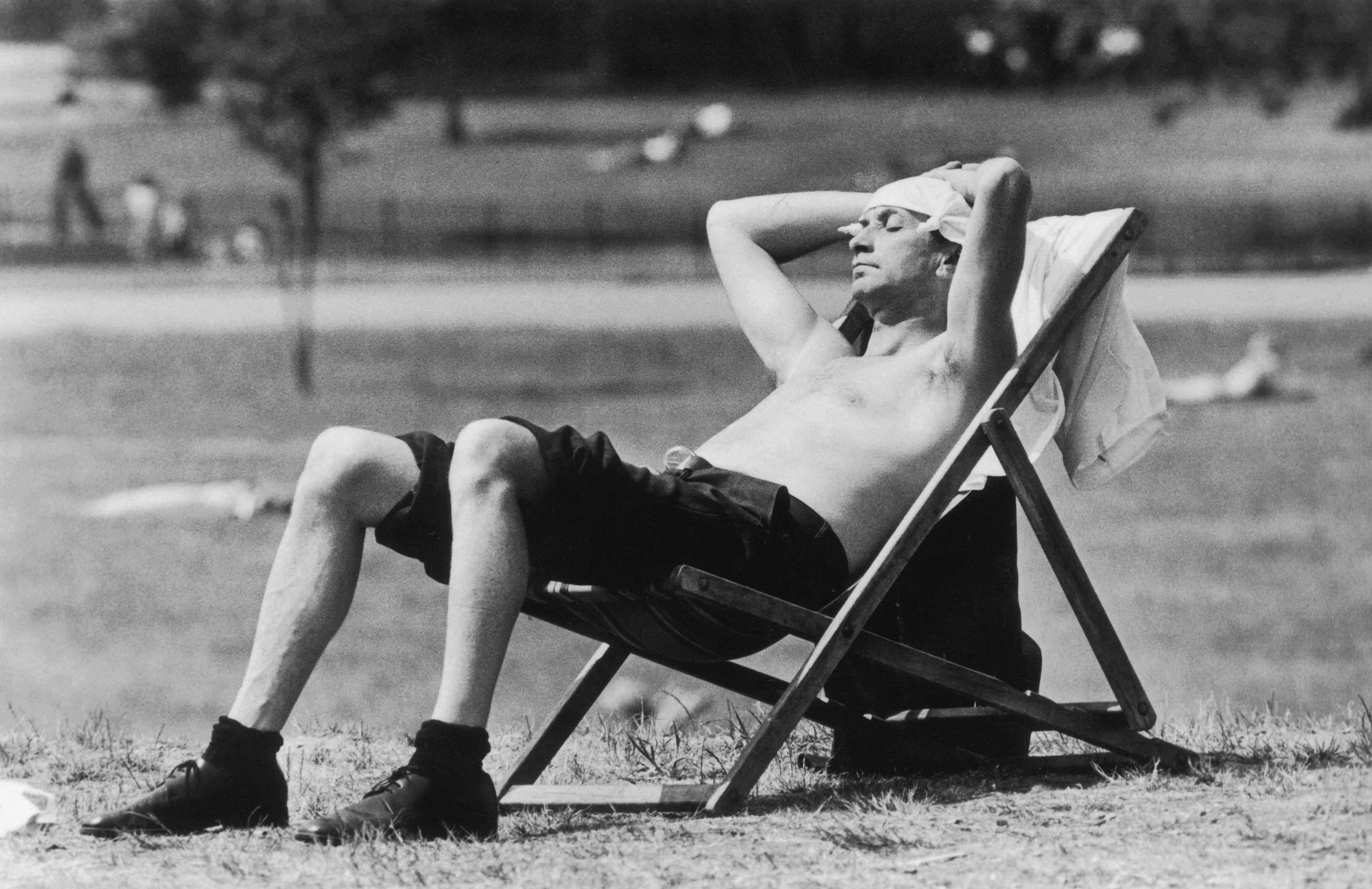 3rd June 1976:  A Londoner sunbathing in Kensington Gardens with a knotted handkerchief protecting his head from the sunshine  (Graham Wood/Evening Standard/Getty Images)