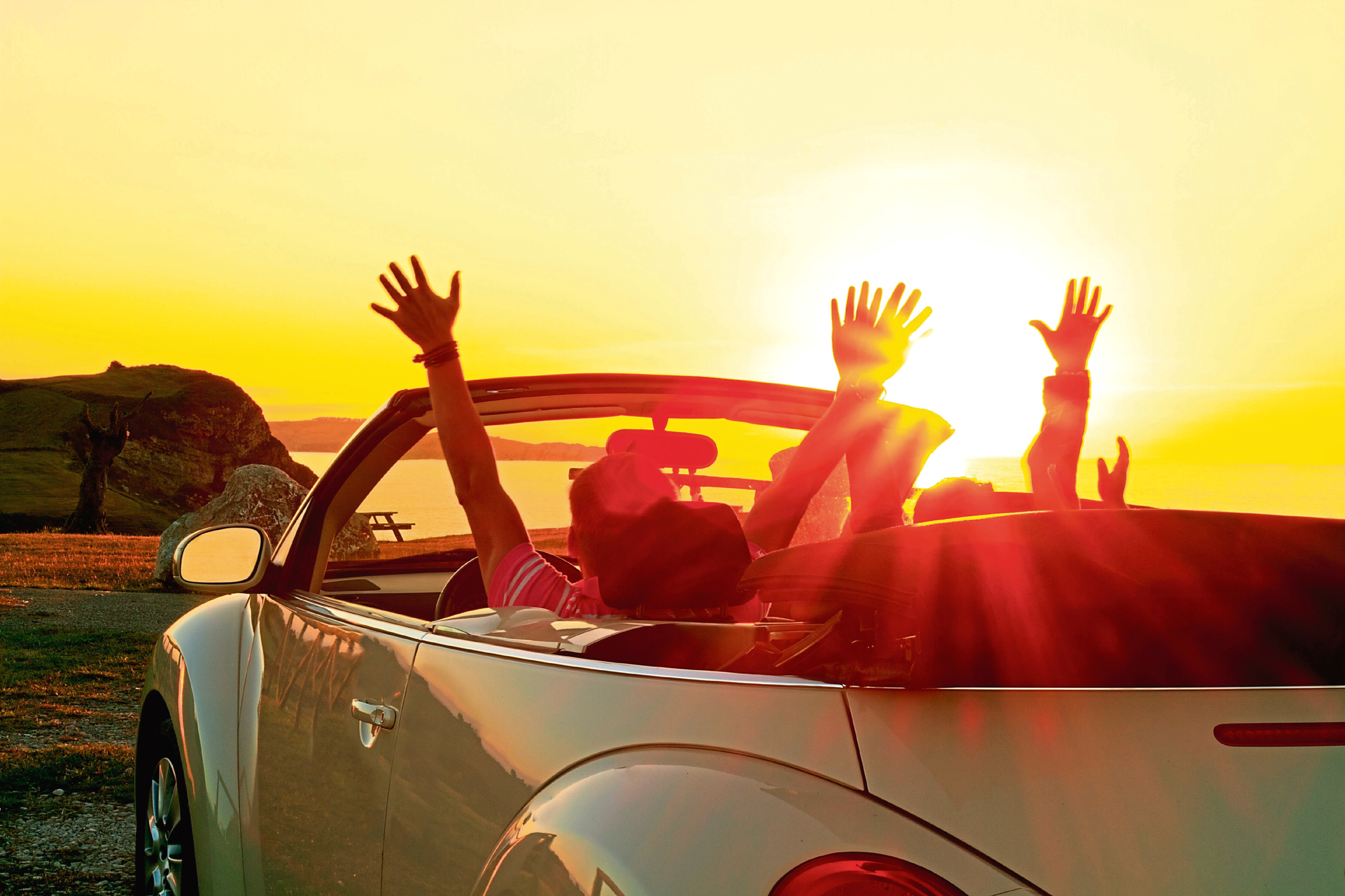 DEH00A Happy family in a cabriolet convertible car at the sunset in summer