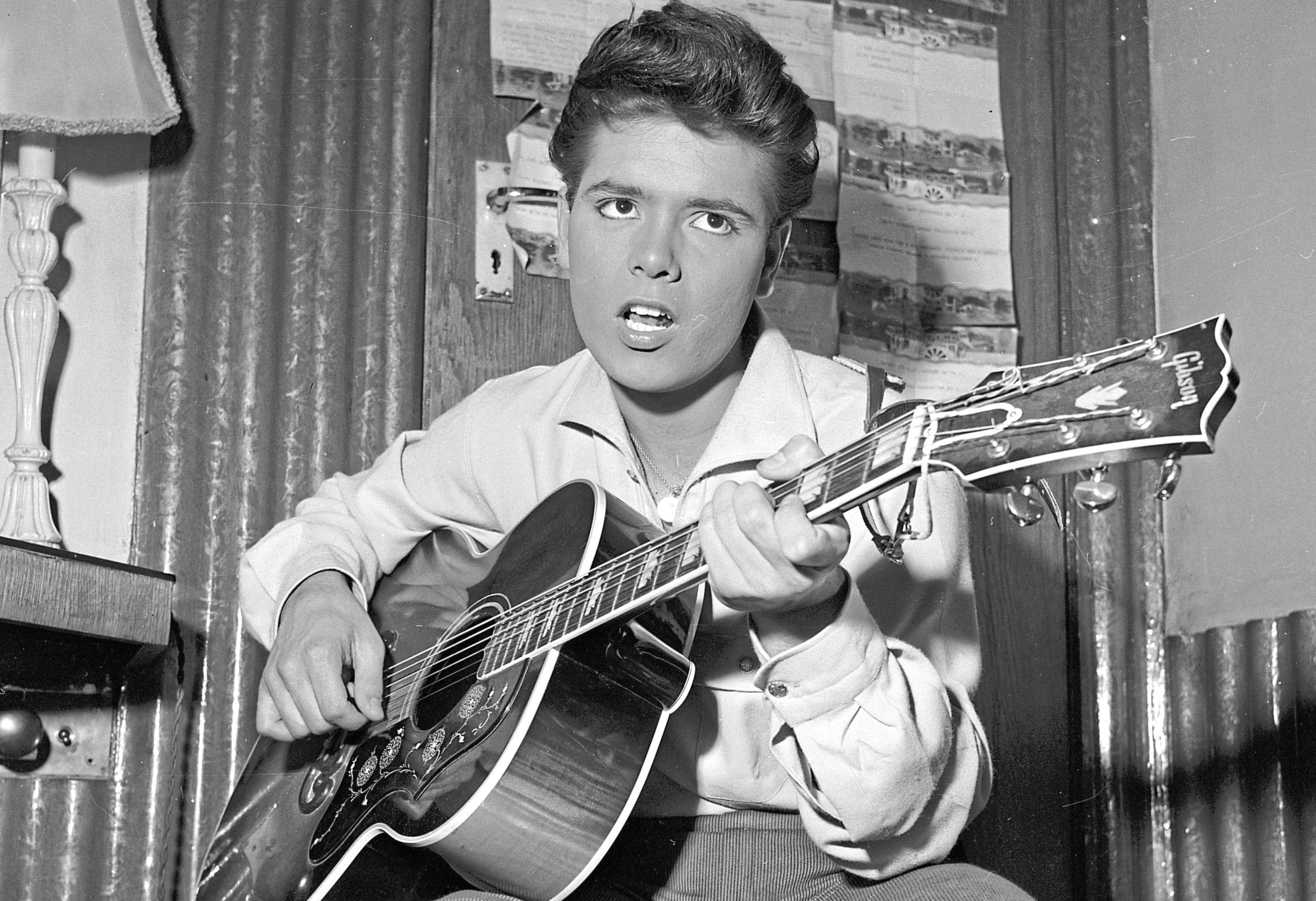 5th August 1960:  English pop star Cliff Richard strums a tune on his trusty guitar before a concert.  (John Pratt/Keystone Features/Getty Images)