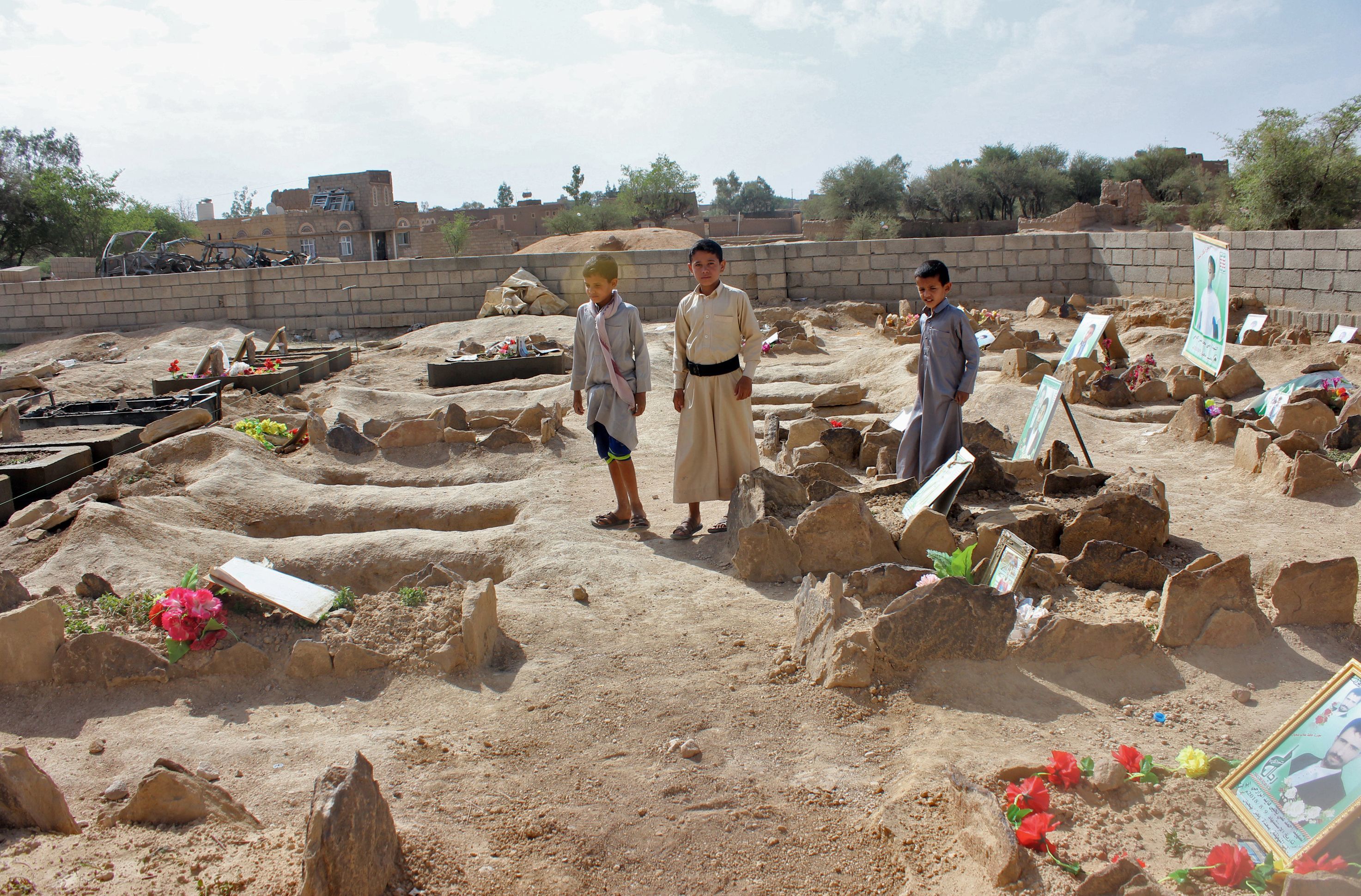 Yemeni children stand by the graves of schoolboys who were killed while on a bus that was hit by a Saudi-led coalition air strike on the Dahyan market in August. (Getty images)
