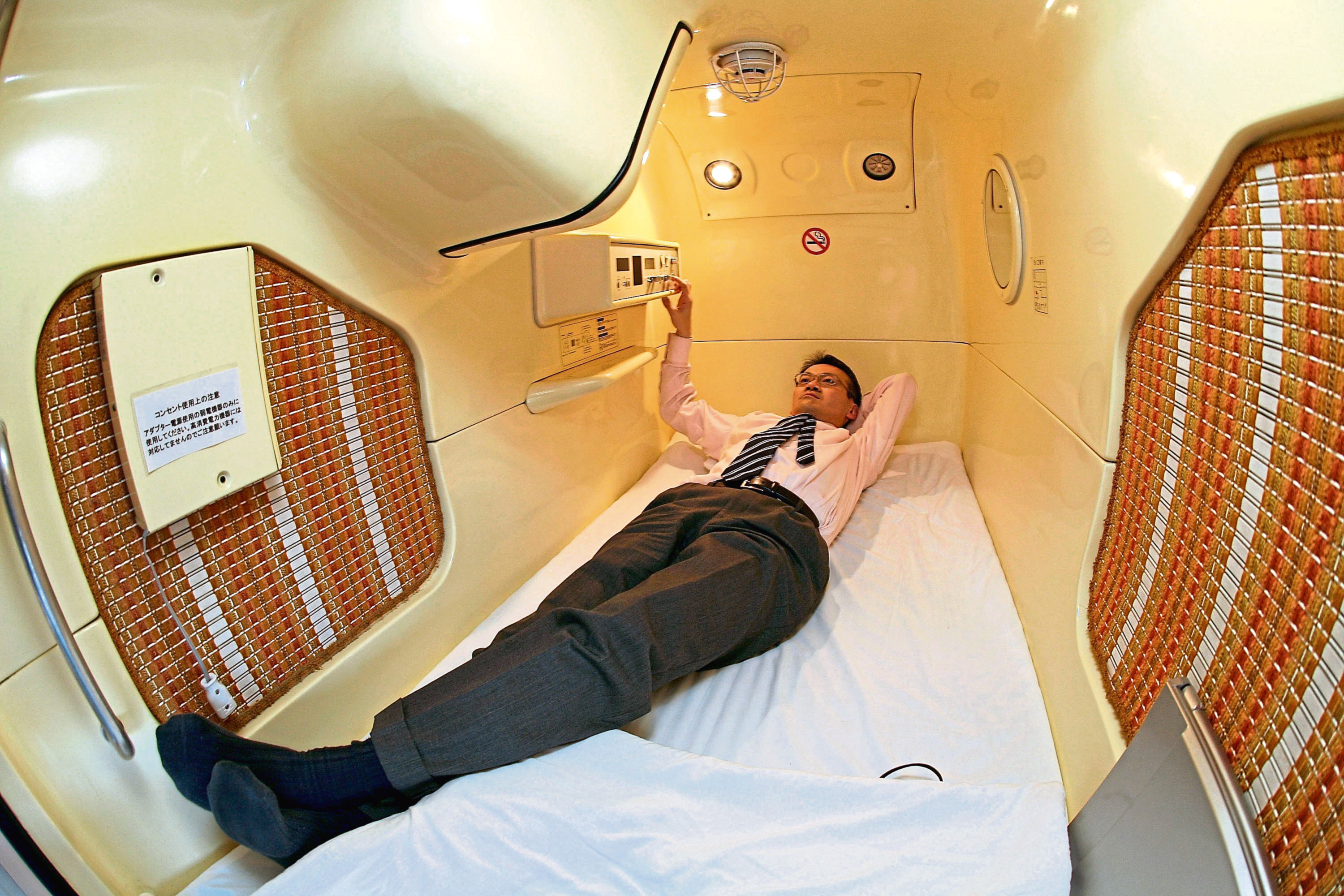 TOKYO - FEBRUARY 6: A visitor relaxes in a sleeping module at Tokyo's tube Hotel "Capsule Inn Akihabara" on February 6, 2007 in Tokyo, Japan. The two-square-meter sleep modules are equipped with a TV, Radio and Wireless LAN and are priced at 3500 yen per night. Uptil recently it has mainly been the office workers who stay at such tube hotels when they cannot go home, but recently they are attracting many foreign travellers due to their Japanese style. (Photo by Koichi Kamoshida/Getty Images)