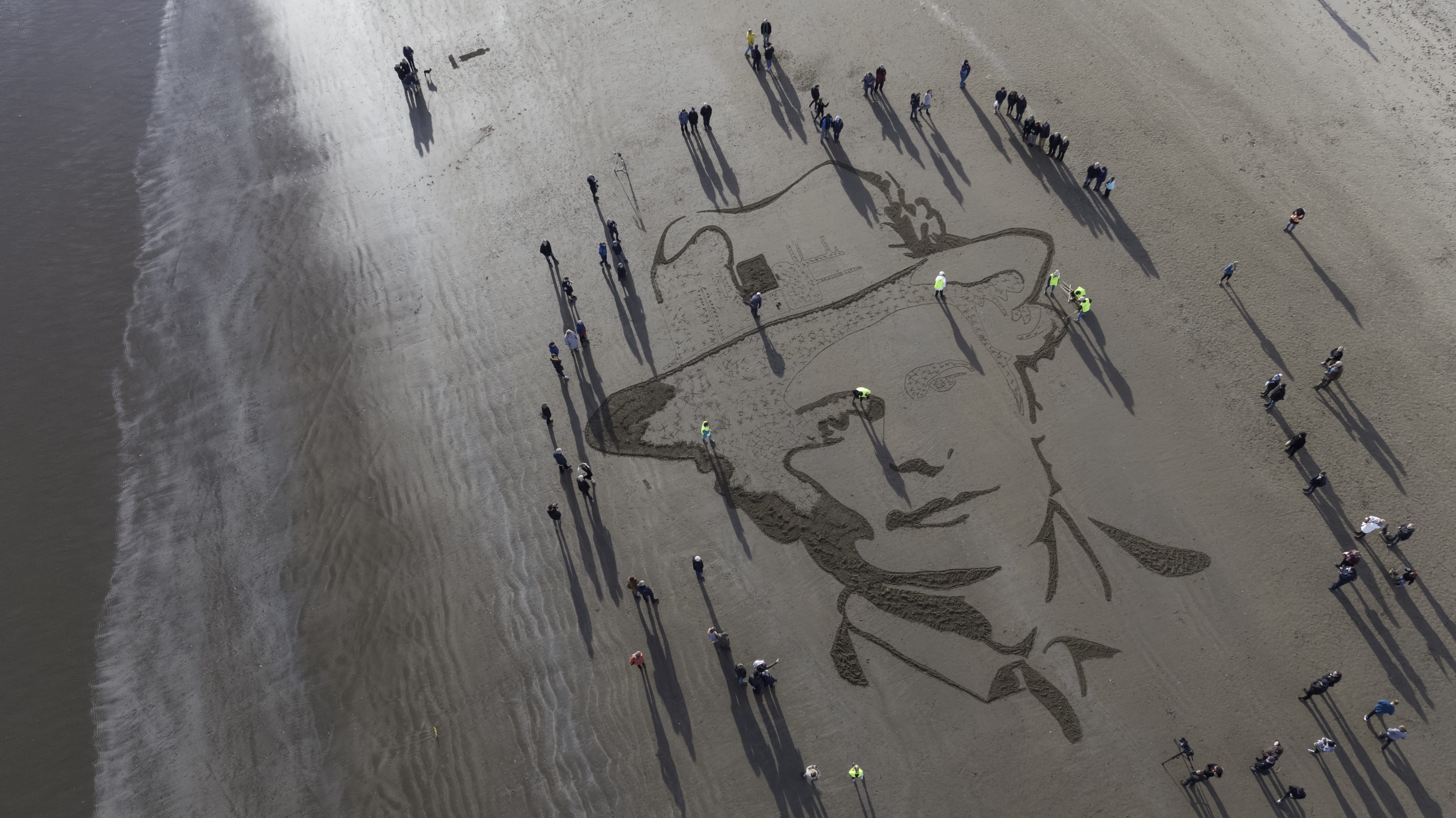 Portrait in progress. Hundreds of spectators look on as a large scale portrait of Dr Elsie Inglis who set up hospitals during WW1 is created on West Sands Beach in St Andrews.