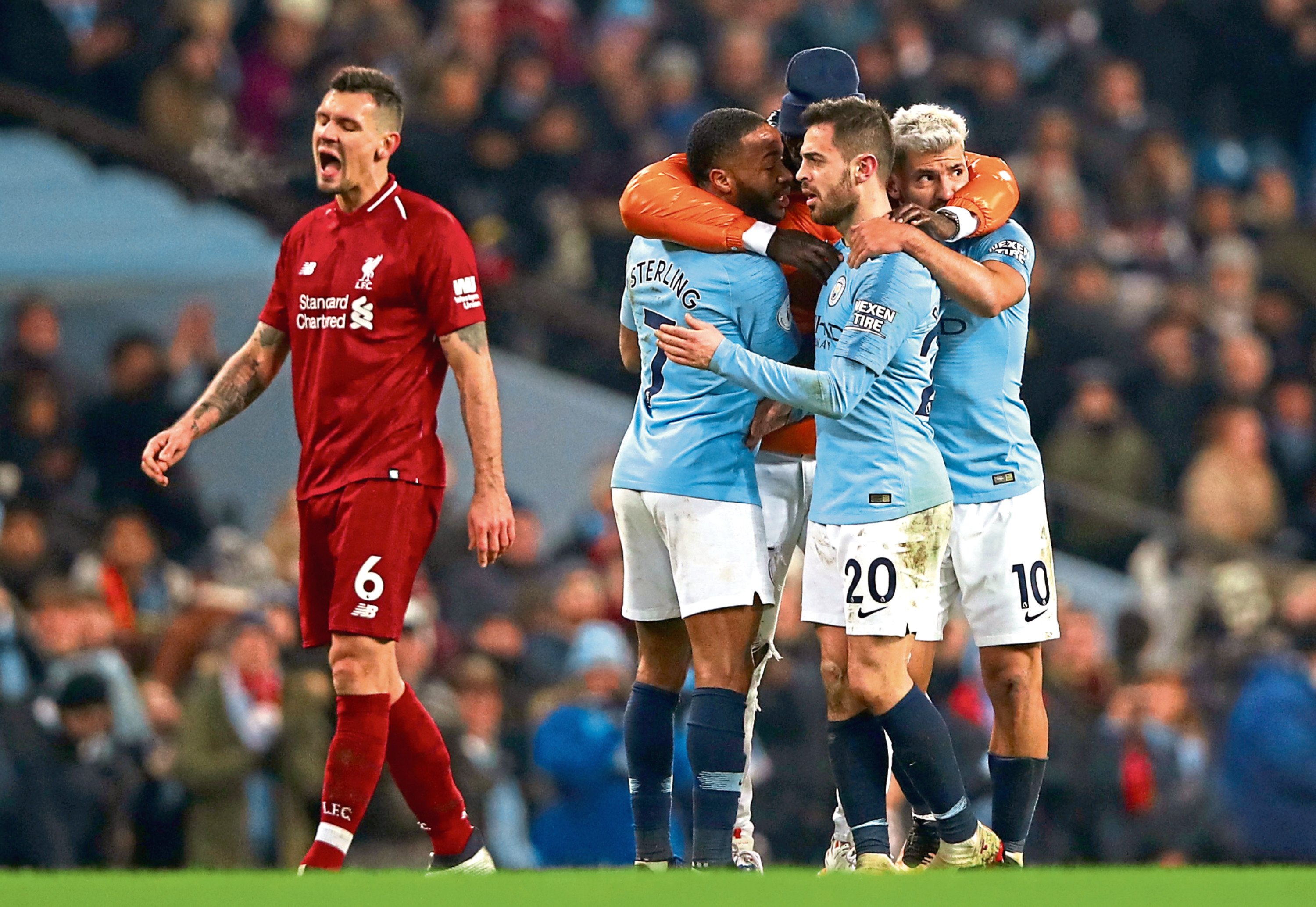 Manchester City’s stars celebrate Thursday night’s win as Liverpool’s Dejan Lovren suffers (Photo by Clive Brunskill/Getty Images)