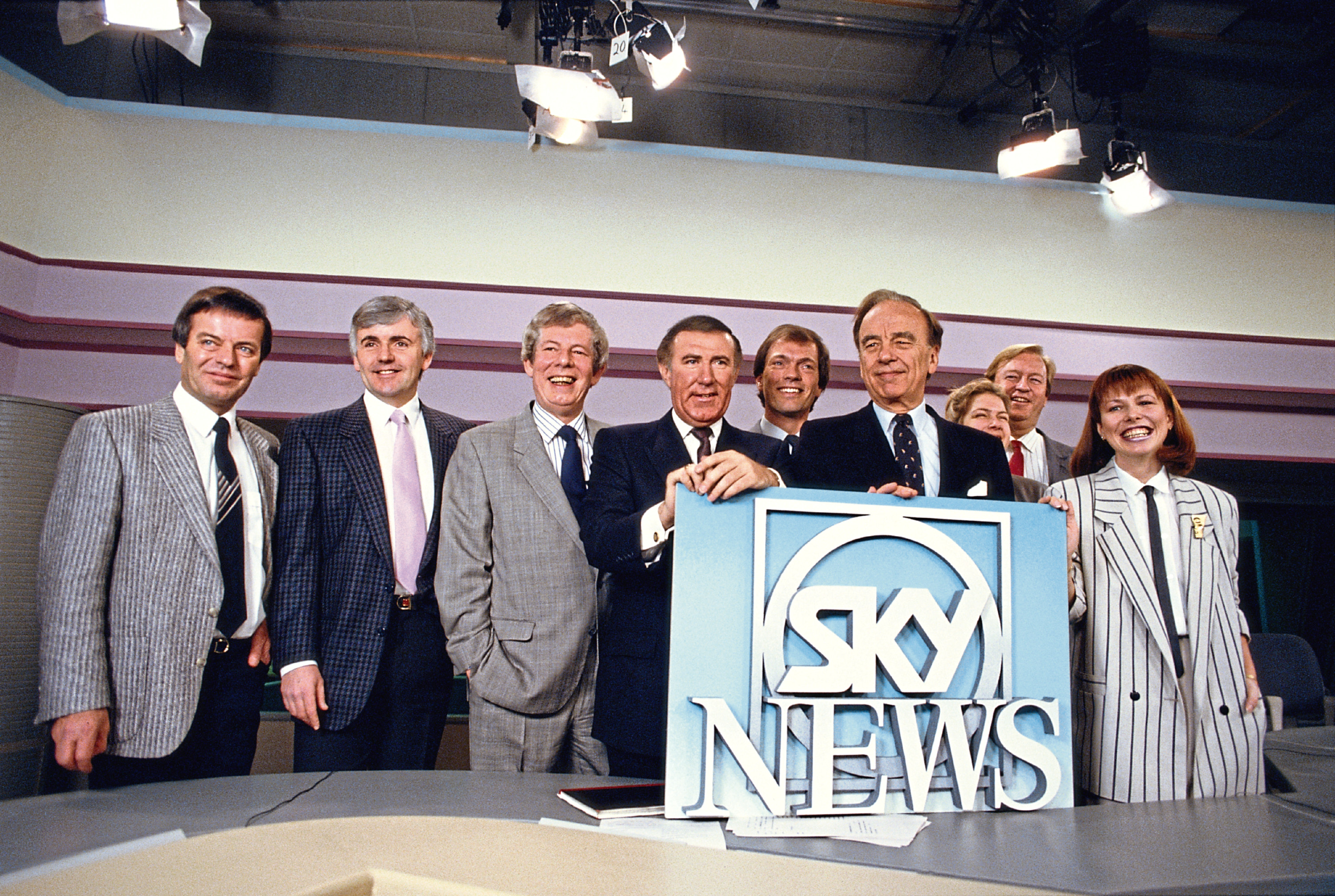 Media magnate Rupert Murdoch and broadcaster Andrew Neil at the launch of Sky TV in London, 5th February 1989. From left to right, Tony Blackburn, Peter Marshall, Derek Jameson, Neil, Alastair Yates, Murdoch, Penny Smith, Bob Friend and Kay Burley.  (Georges De Keerle/Getty Images)