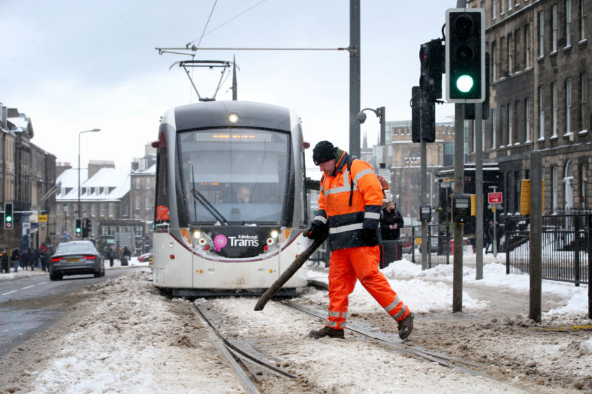 An engineer clears snow and ice from the tram lines along York Place in Edinburgh