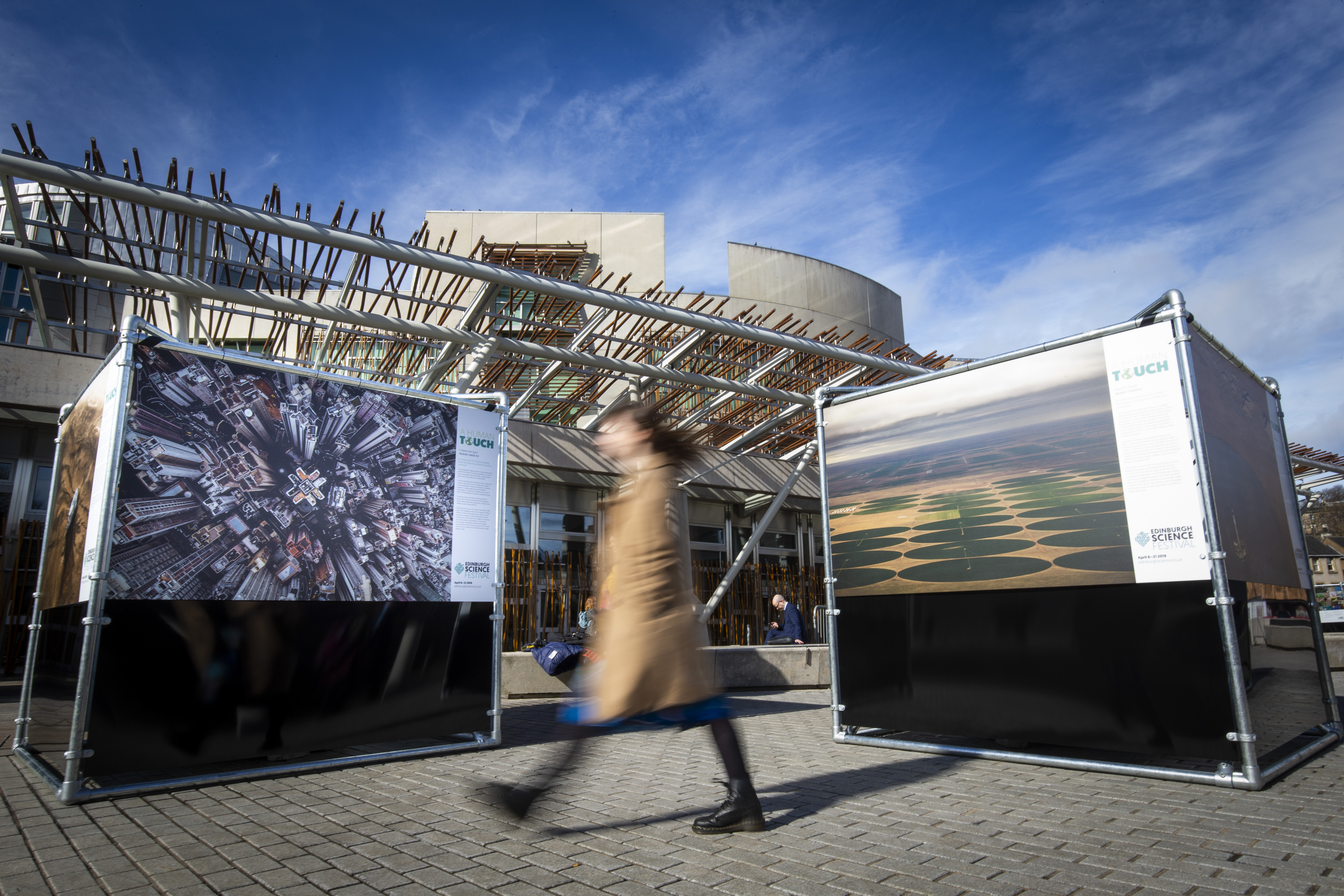 A member of the public admires the large-scale, outdoor photography exhibition showcasing the impact humans have on planet Earth is unveiled today at The Scottish Parliament.
