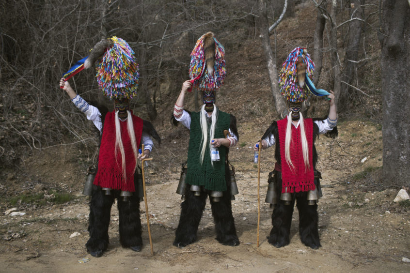 Men wearing goat hides with bells around their waist and masks that include a meter tall, ribbon-covered formation topped with a foxtail, also known as bell wearers, pose for a photo at the village of Sohos, northern Greece as they participate in a Clean Monday festival
