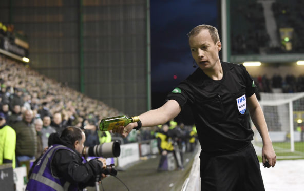 Referee Willie Collum removes a bottle from the pitch, which was thrown from the stands