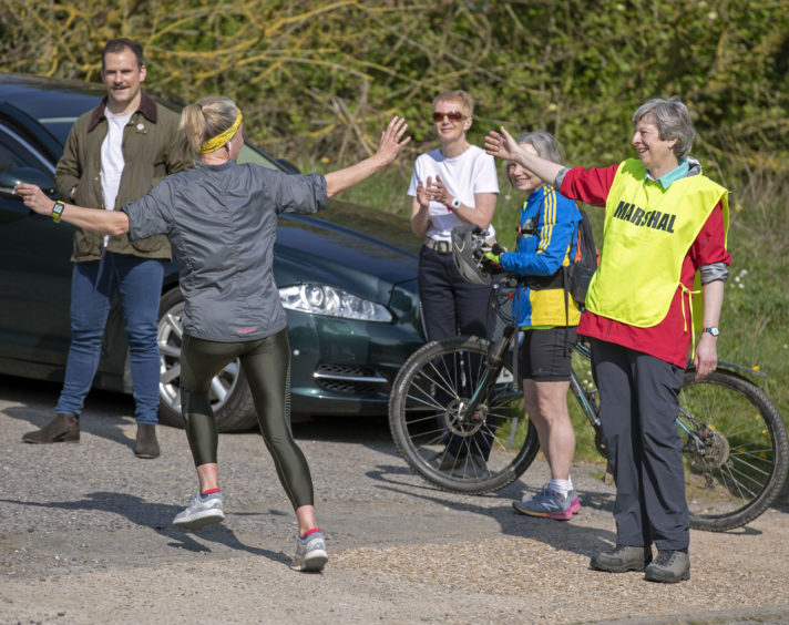 Prime Minister Theresa May chats with a runner as she joins a team marshalling the Maidenhead Easter 10k race, a popular annual event in her constituency