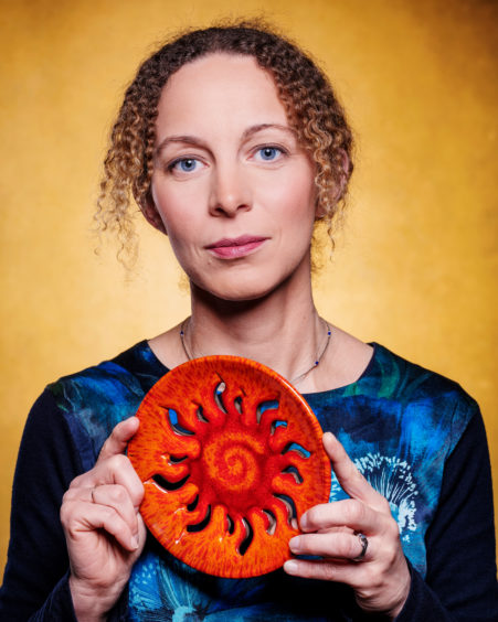 BELGIUM: Prof Ineke DeMoortel FRSE, University of St Andrews, a solar physicist who applies mathematics to understand things in nature. She uses equations describing fluids and magnetic fields to understand more about the solar atmosphere.

Ineke is holding a pottery plate depicting the sun