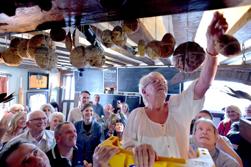 Margaret Utteridge, 74, who works at The Bell Inn in Essex, hangs a hot cross 
bun from a beam, continuing a tradition stretching back more than a century