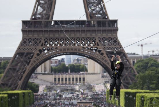A woman zipslides from the Eiffel Tower