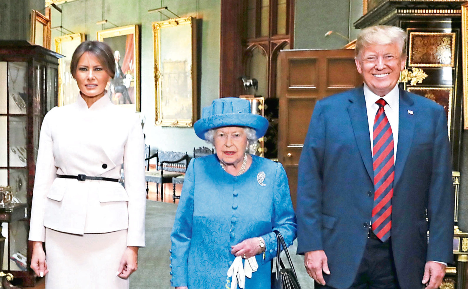 Queen Elizabeth II stands with US President Donald Trump and his wife, Melania, in the Grand Corridor during their visit to Windsor Castle in Berkshire last year