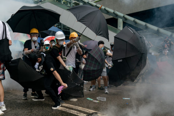 Hong Kong protesters wield umbrellas                as security forces fire pepper spray last week