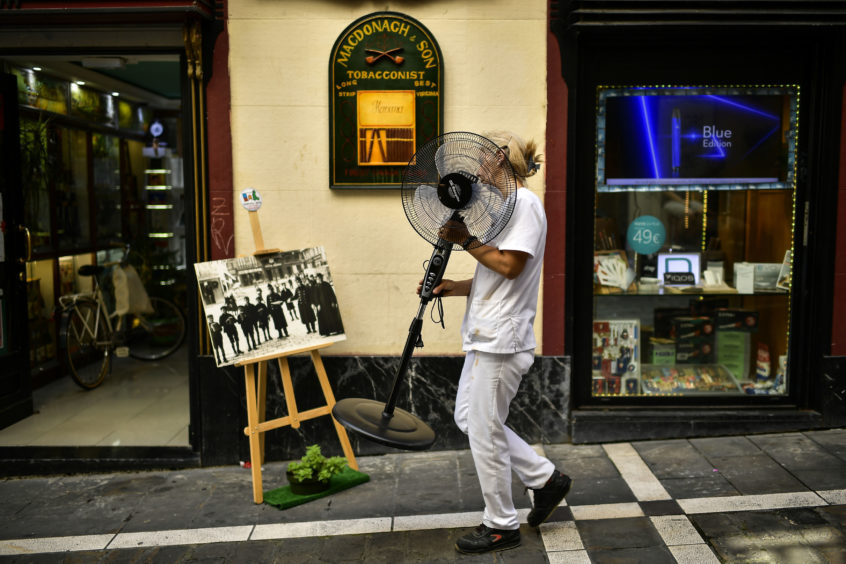 A woman carries a fan during a hot summer day in Pamplona, northern Spain