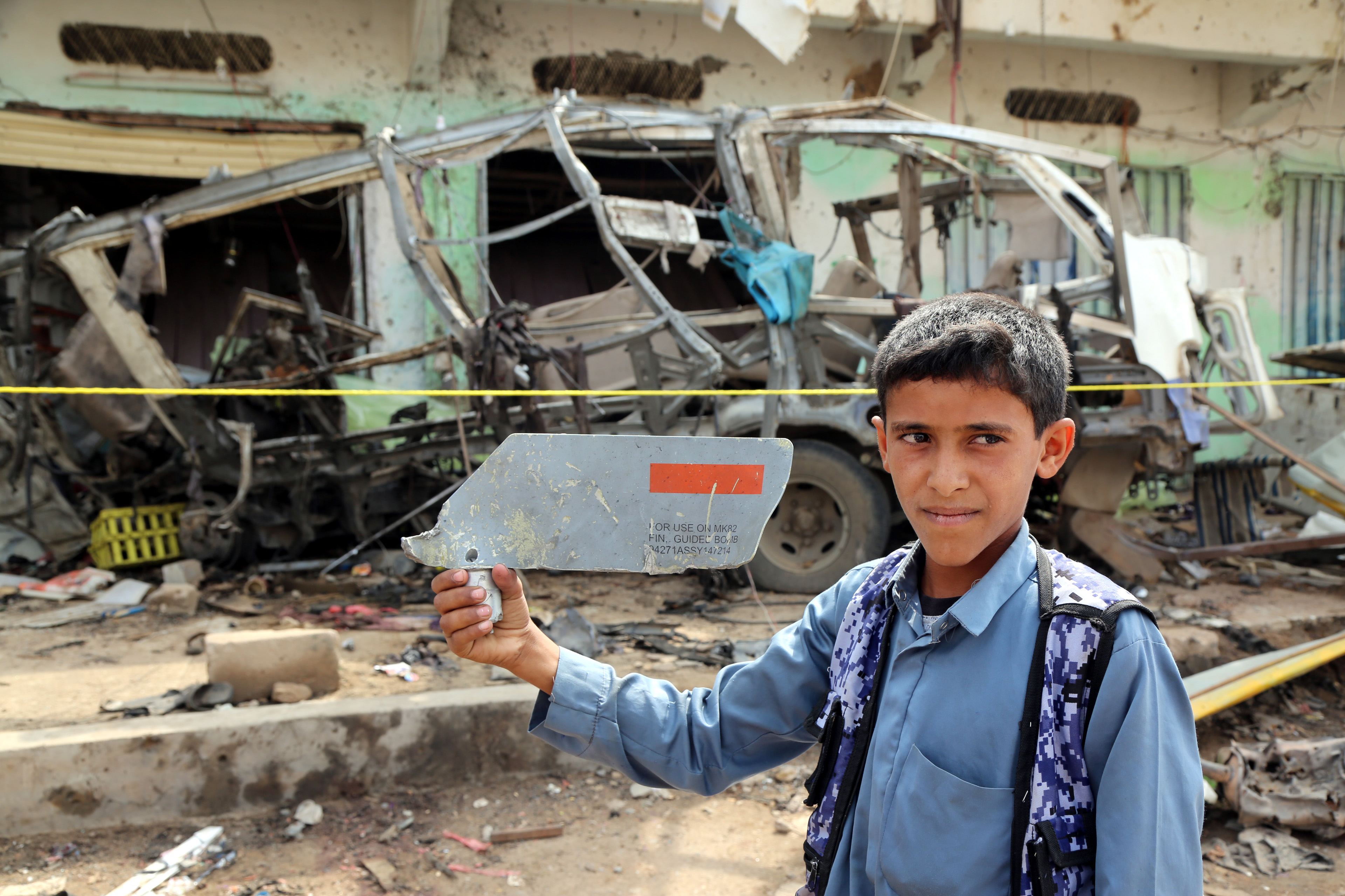A child displays a part of a missile that hit a bus killing dozens of children in Yemen August last year