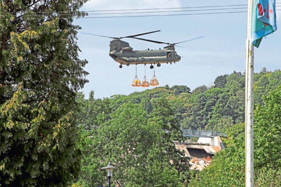 An RAF Chinook helicopter flies in sandbags to help repair the dam at Toddbrook reservoir near the village of Whaley Bridge in Derbyshire