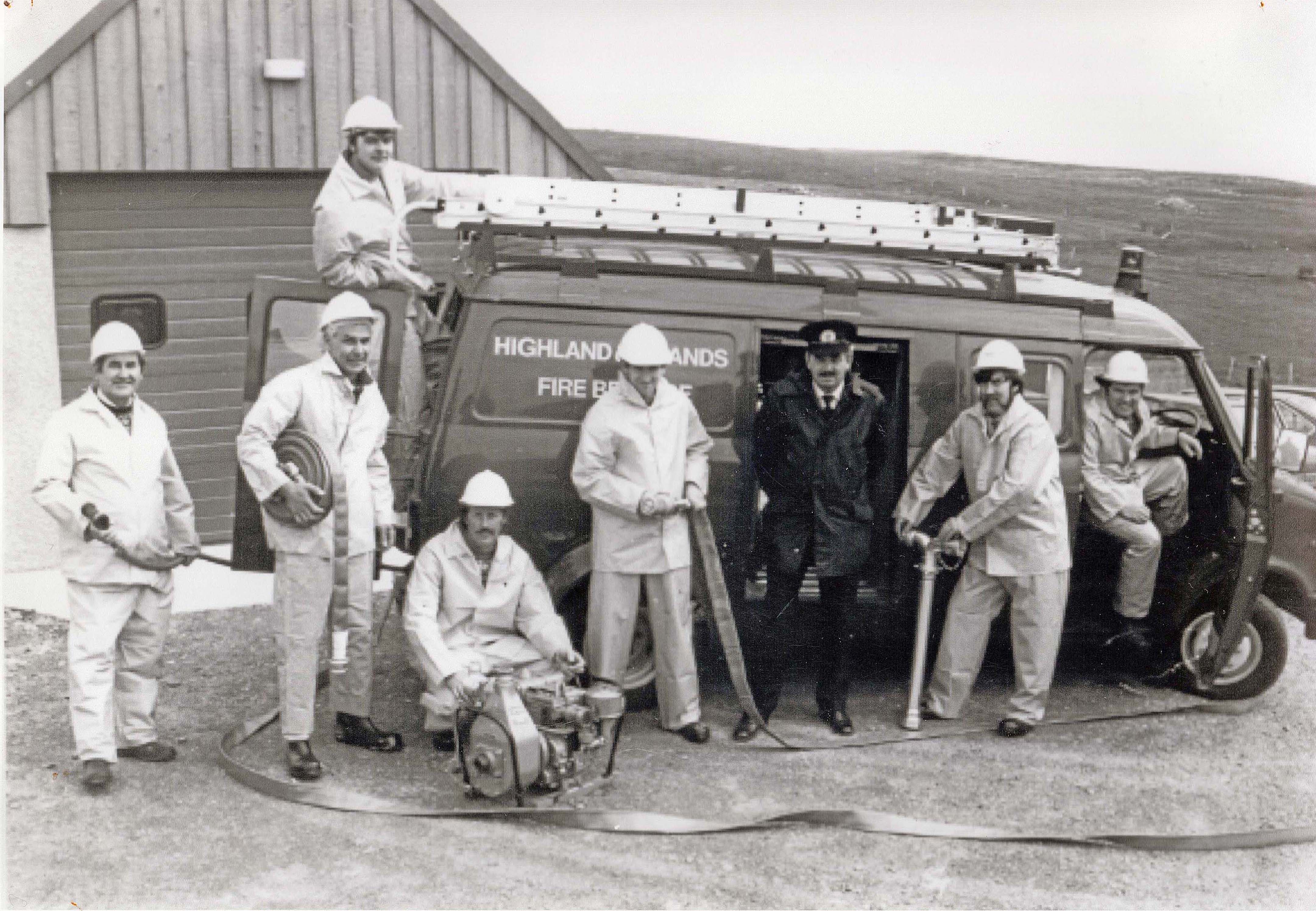 Highlands and Island Fire brigade reunion. the original picture taken i  1986. l-r David Arthur,Andrew Williamson ( with hose), James Anderson, Tom Shearer, John Simpson, the divisional fire commander (name unknown), Charlie Hutchison and George Leask. This picture was taken in 1986, and has been reproduced in  an almost ideintical picture taken in 2019.