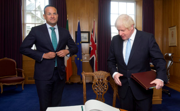 Prime Minister Boris Johnson prepares to sign the visitor's book as Taoiseach Leo Varadkar welcomes him to the Government Buildings during his visit.