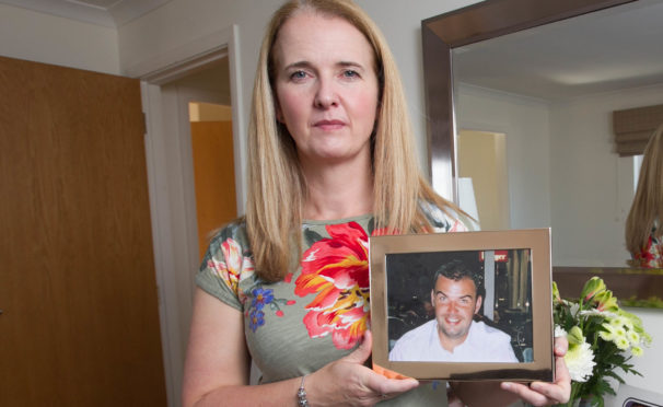 Louise Taggart at home in Edinburgh holding photo of brother Michael Adamson