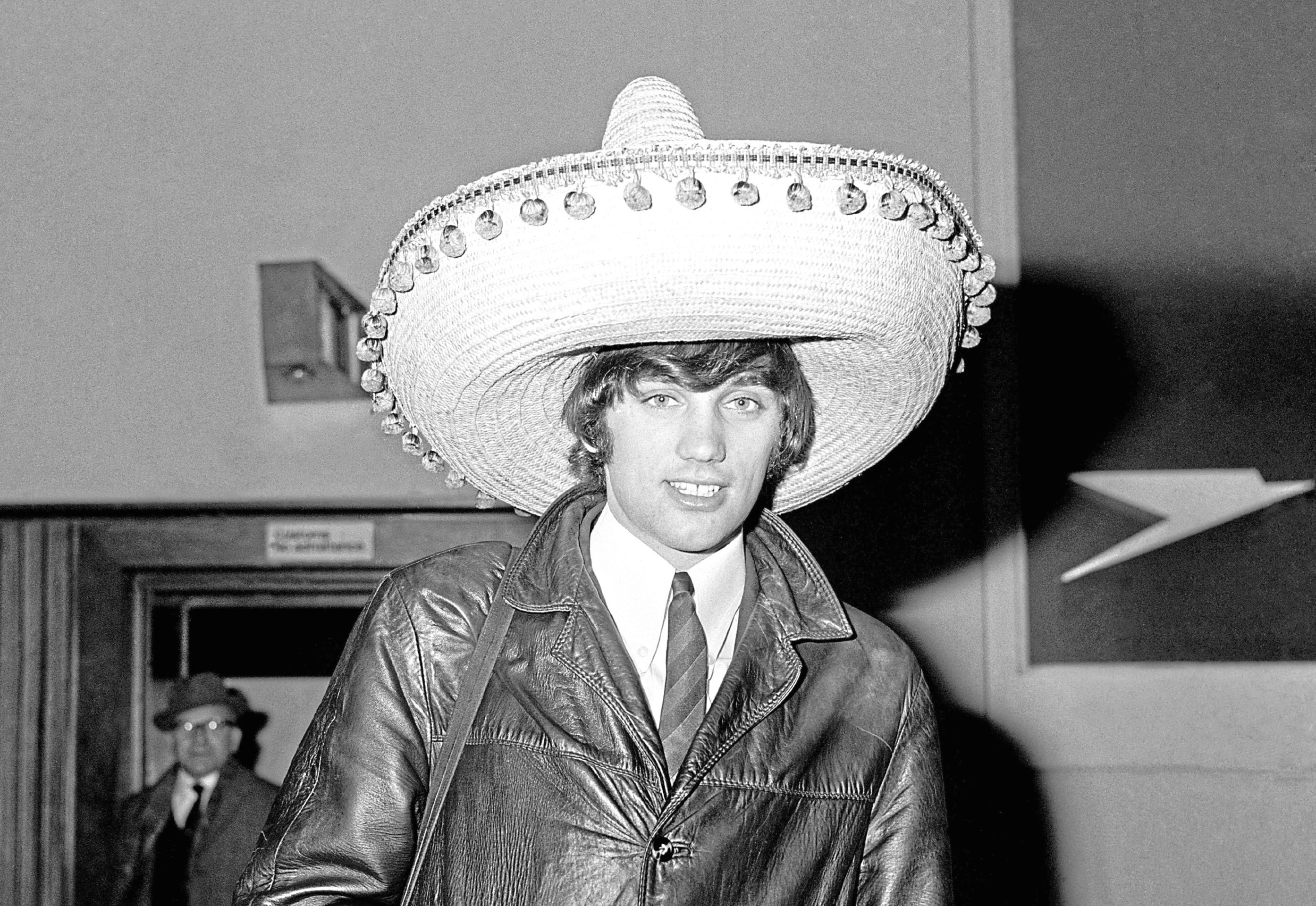 Manchester United footballer George Best wearing a Souvenir Sombrero on his return to London airport following United's defeat of Benfica 5-1 in the second leg of the European Cup quarter final football match. Best scored United's first two goals.