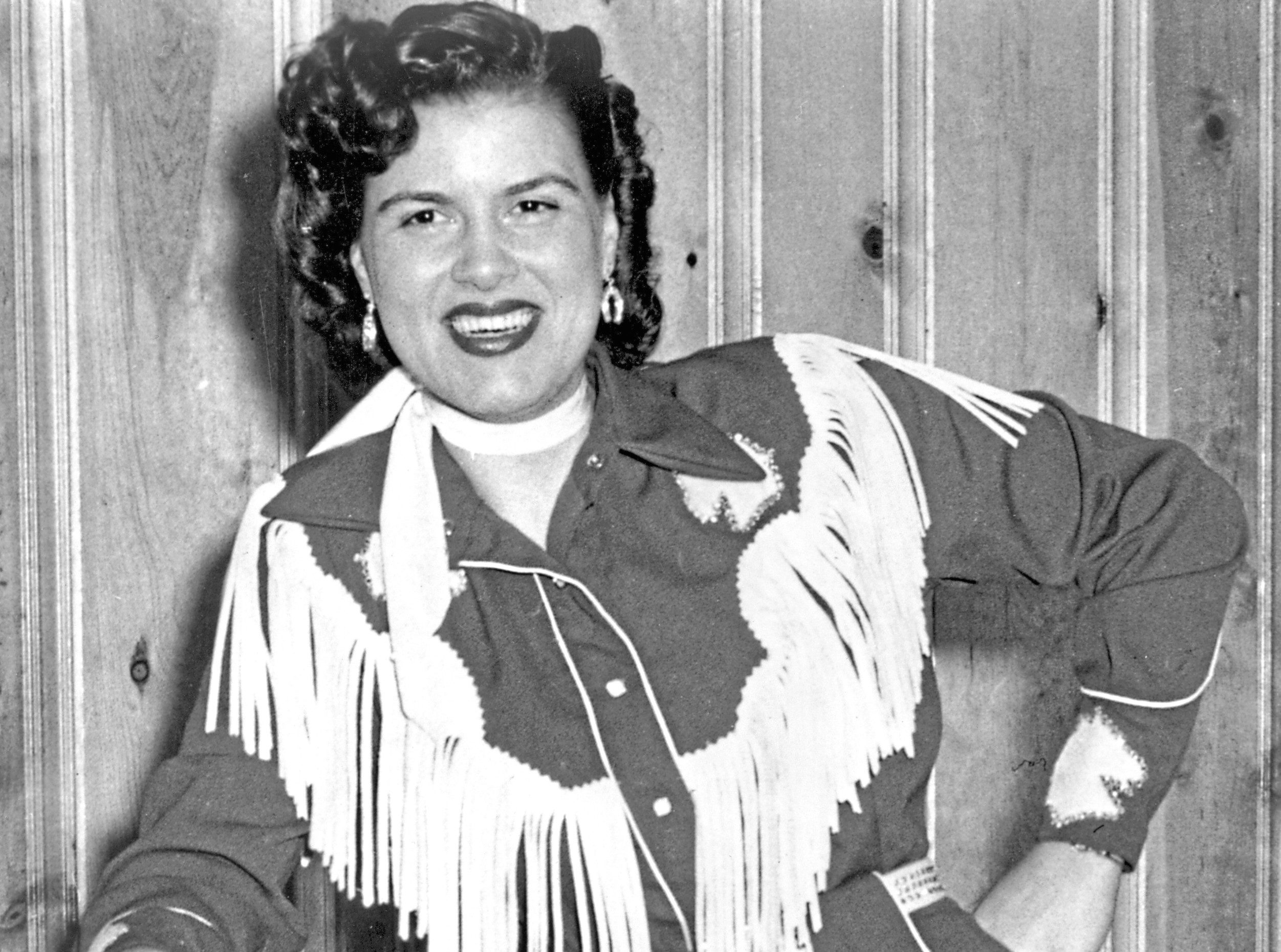 CIRCA 1958:  Country musician Patsy Cline plays the piano wearing a fringed dress and holding a cowboy hat in circa 1958.