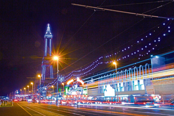 The Famous Blackpool Tower and lights along the stretch of promenade known as the Golden Mile in Blackpool, Lancashire at night, photographed on a long exposure with light streaks during the yearly 'illuminations' spectacle.