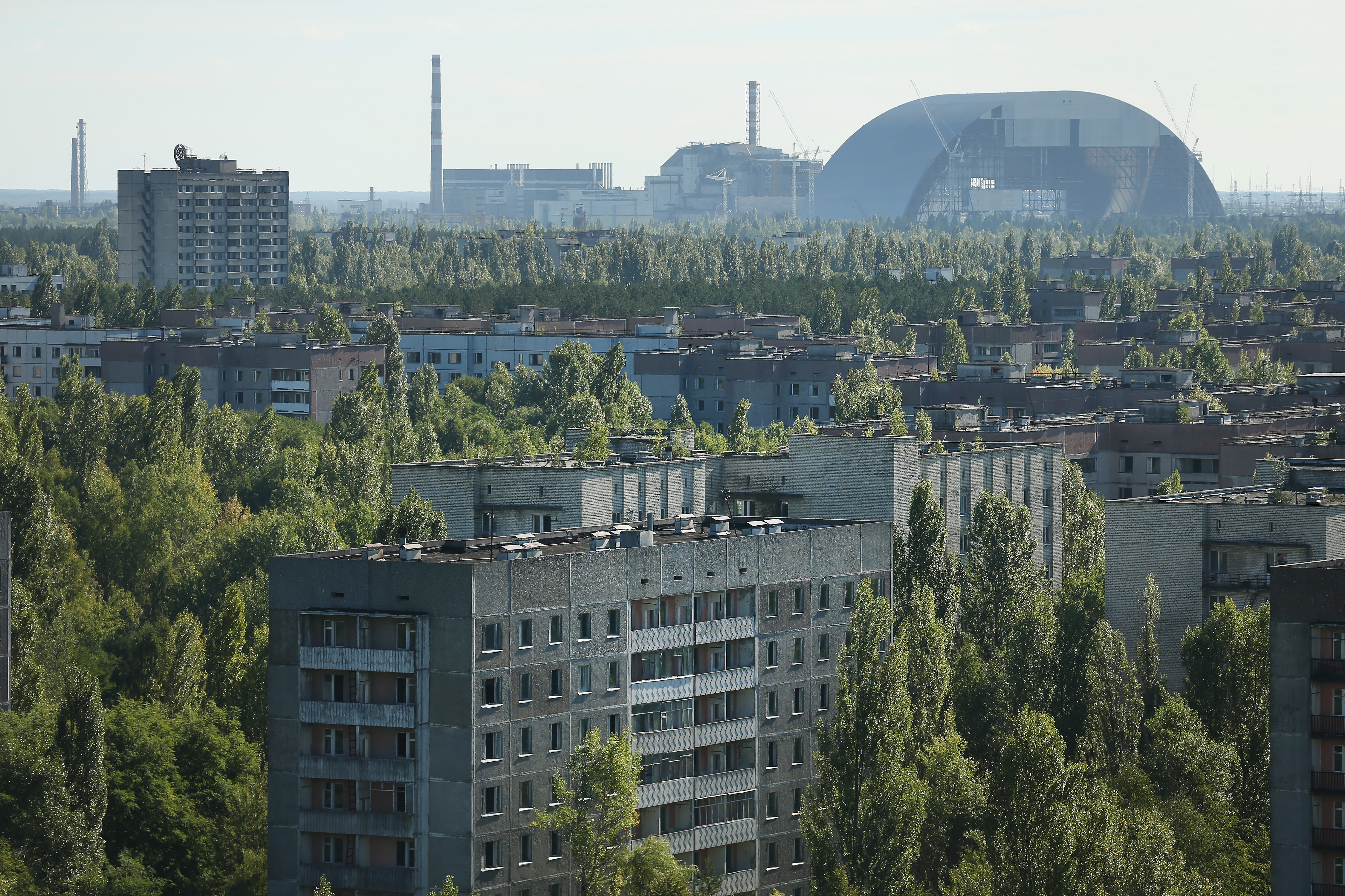The former Chernobyl nuclear power plant, including destroyed reactor four (C), as well as the New Safe Confinement structure (R) that will one day enclose the remains of reactor four, stand behind the abandoned city of Pripyat.
