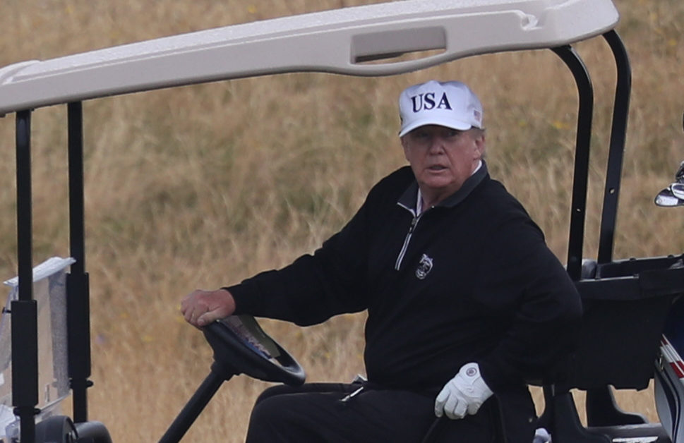 US President Donald Trump drives a golf buggy on his golf course at the Trump Turnberry resort.