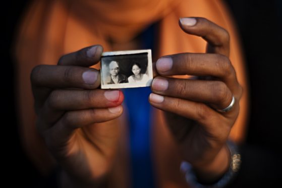 A woman holds a passport photo of lost daughter. An image. A name. A memory. A photograph is often the only thing families have left of their lost daughters..