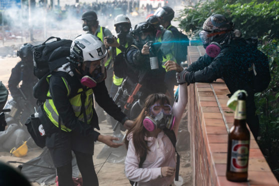 Police officer sprays protesters with identifying blue dye as they try to flee after occupying Hong Kong Polytechnic University campus on Monday