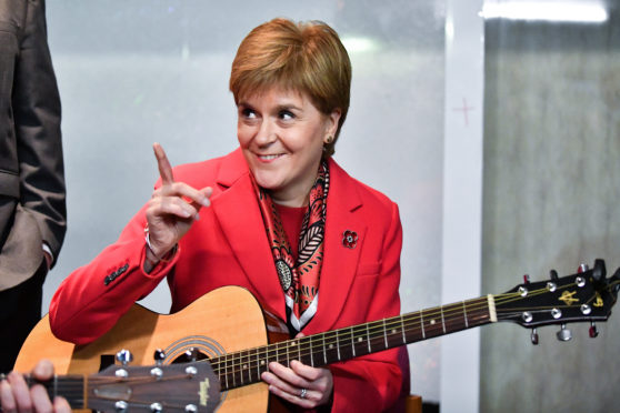 First Minister Nicola Sturgeon holds a guitar as she visits Dalkeith Community Hub