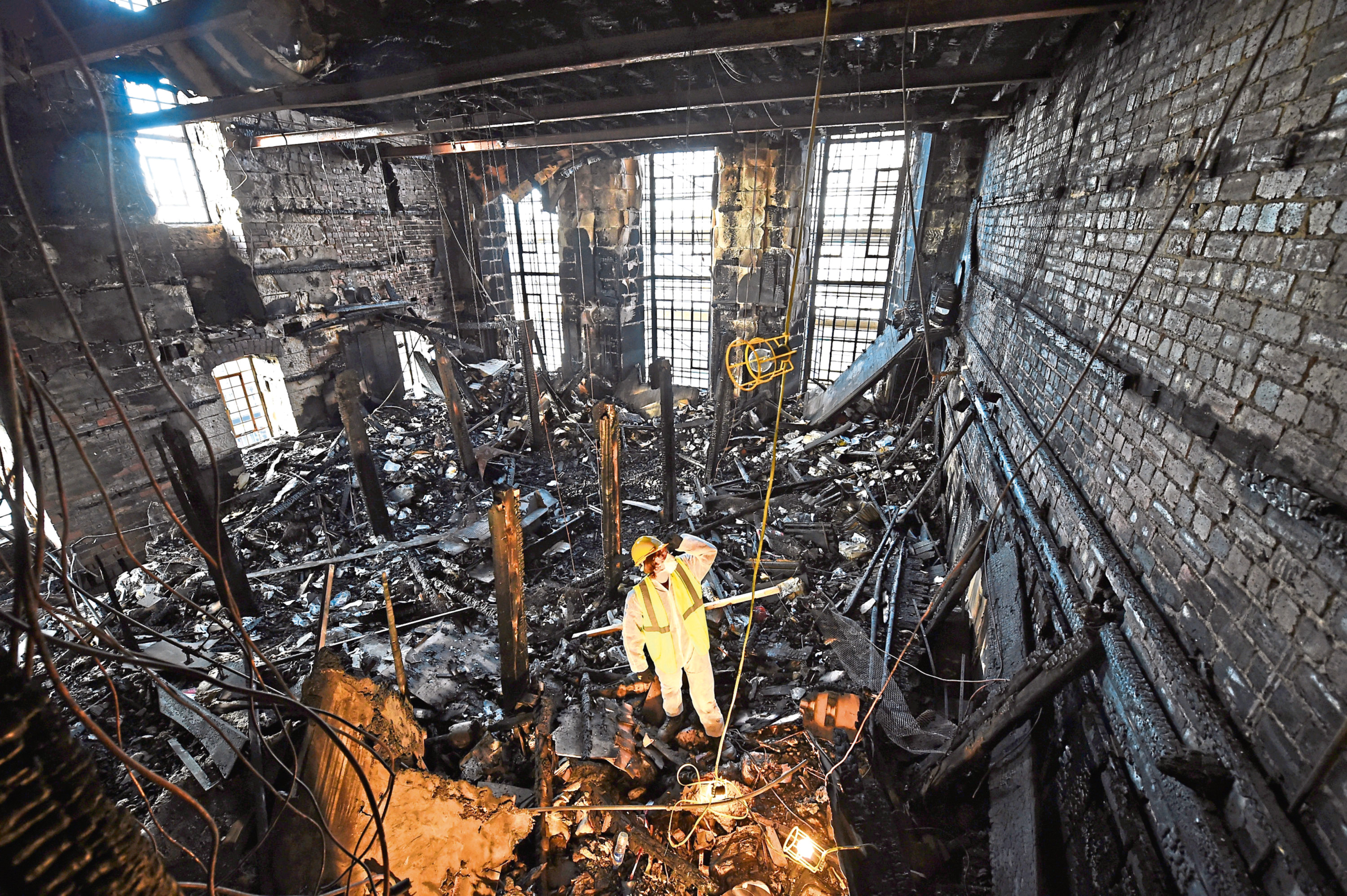 A forensic expert sifts through ashes of the art school library after 2014 fire