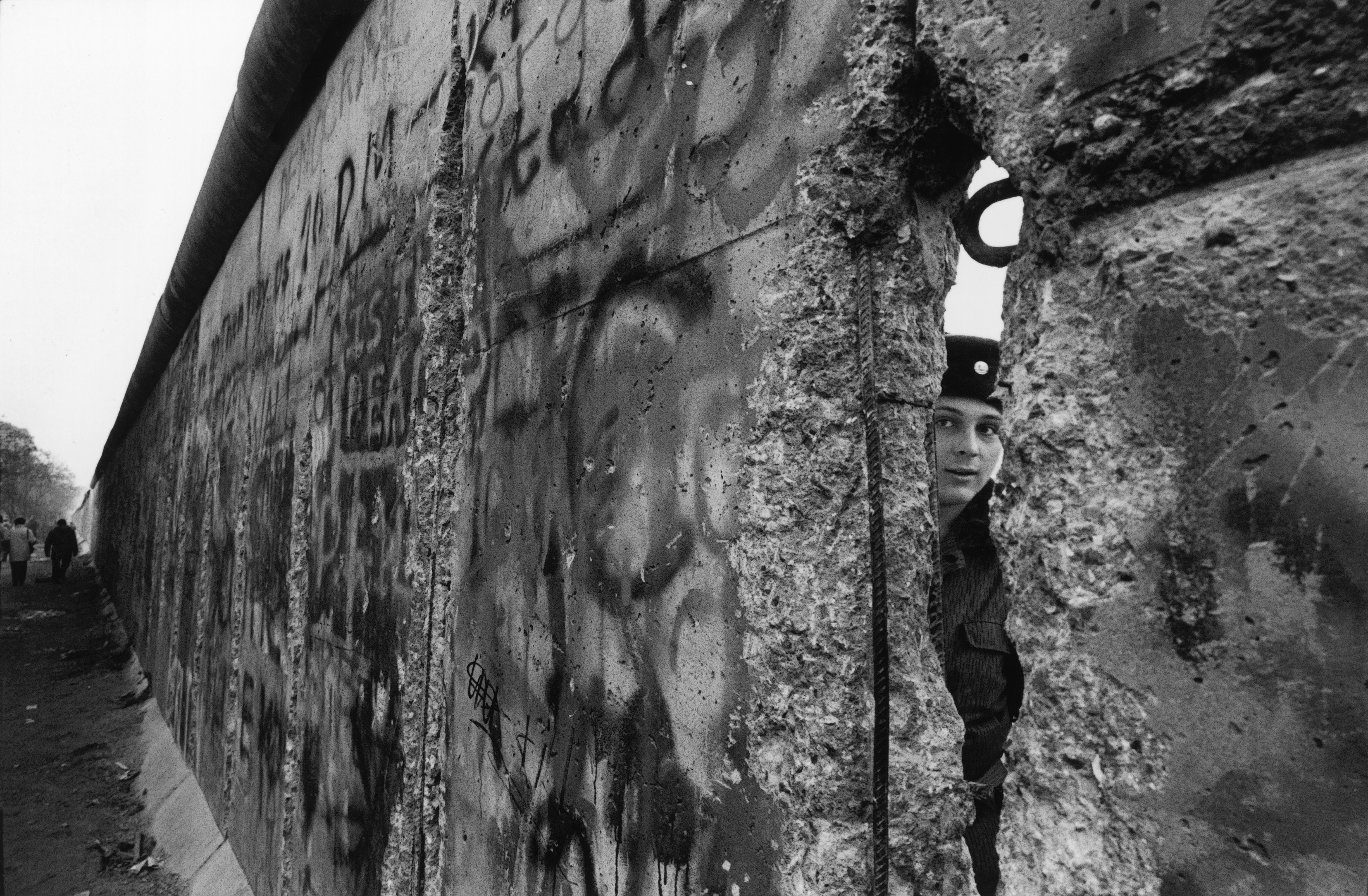 An East German soldier looks through the Berlin Wall in 1989
