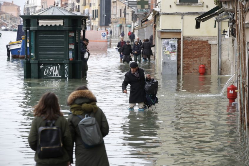 People wade through water during a high tide