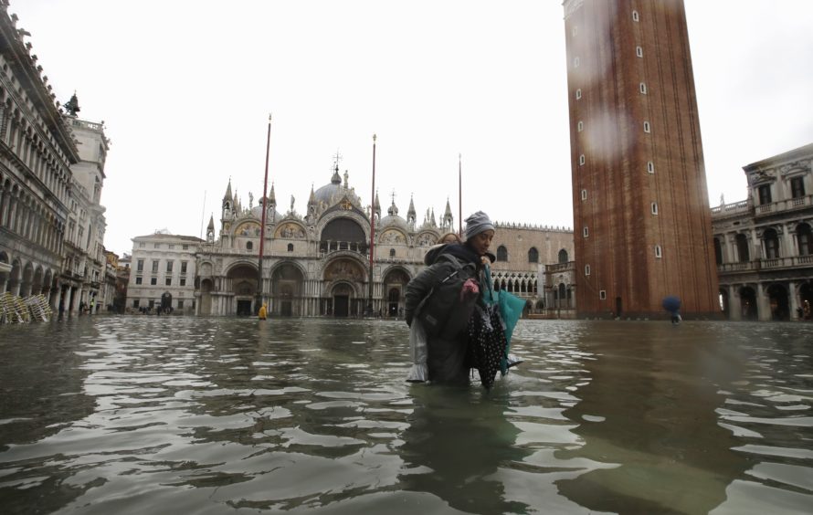 A woman carries her daughter in a flooded Piazza San Marco