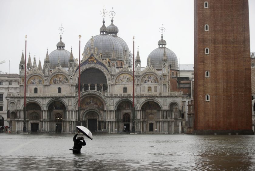 A photographer takes pictures in a flooded Piazza San Marco