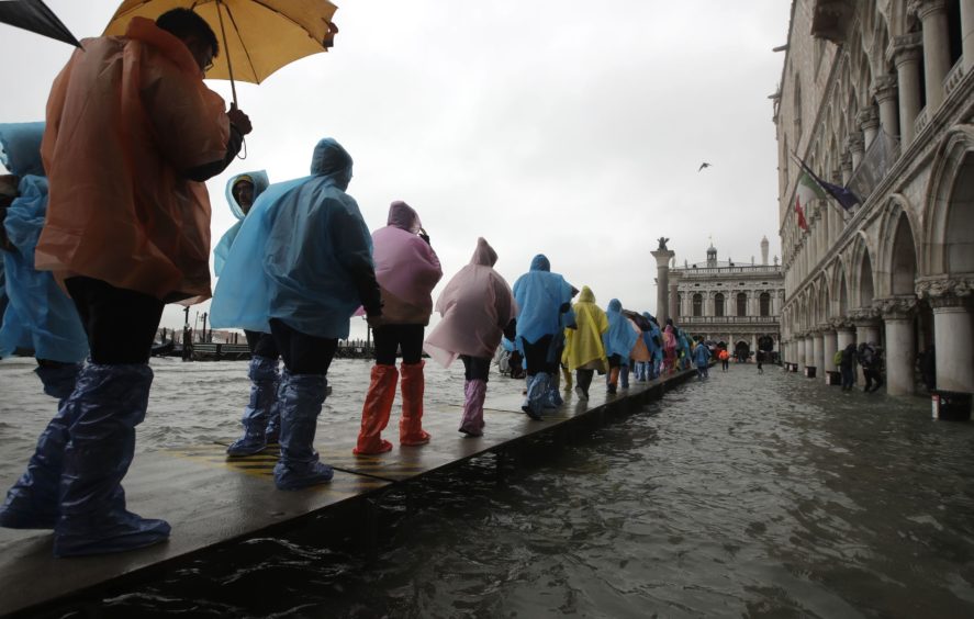 People walk on a catwalk set up due to the floods