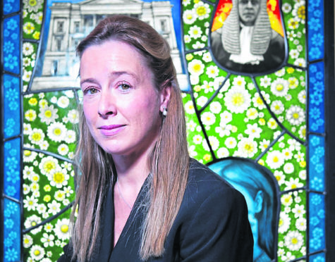 Dr Emma Forbes, with a piece of stained glass on display at the Scottish Parliament, which has been designed with the help of women who have suffered domestic abuse.