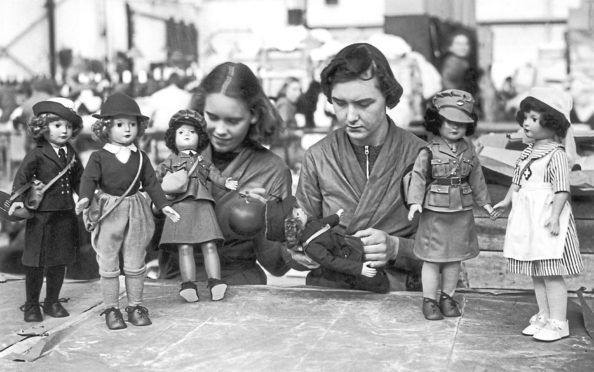 Workers in a British toy factory with dolls dressed in the uniforms of various women's war services, 19th October 1939. The toys are being produced in time for the first Christmas of the war.