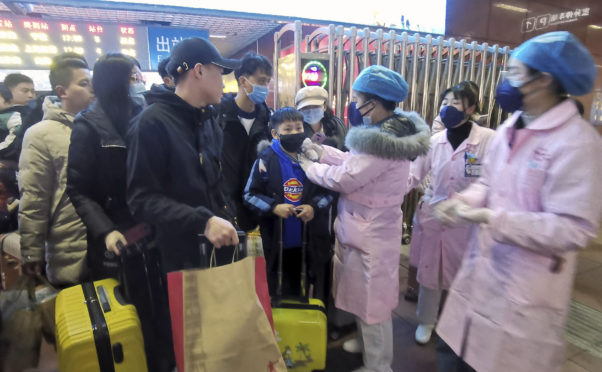 Medical workers use an infrared scanner to check travellers for signs of the coronavirus at a train station in Nanchang in south China on Wednesday