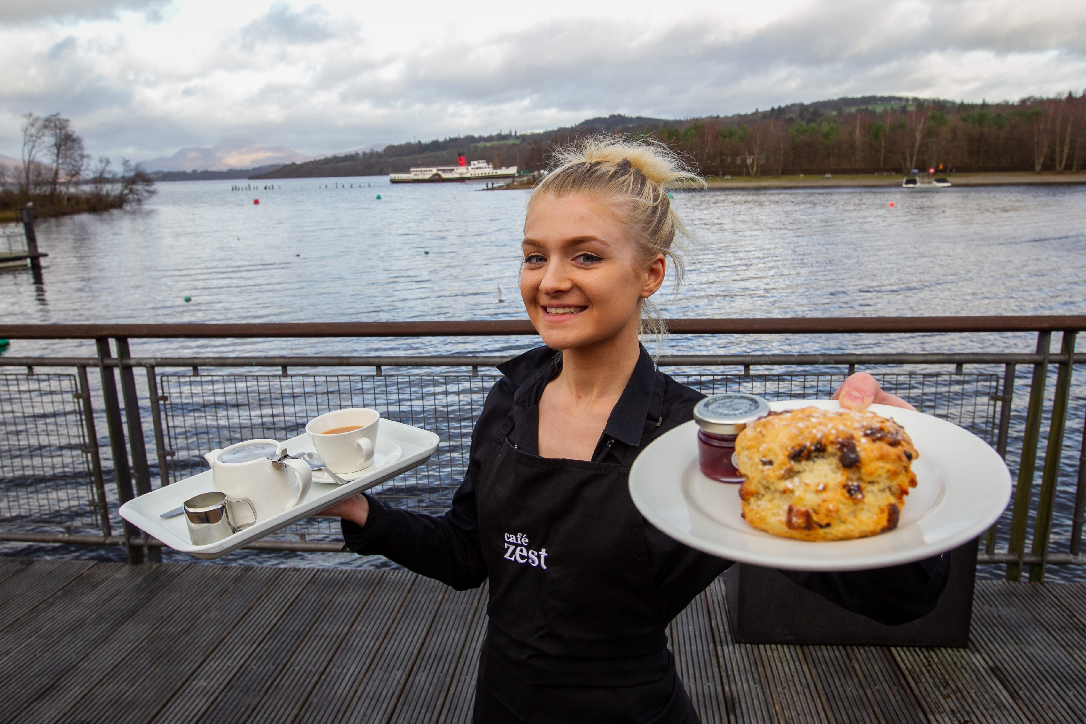 Waitress Catherine, in front of Loch Lomond and the Maid of the Loch paddle steamer, shows off Café Zest’s fare