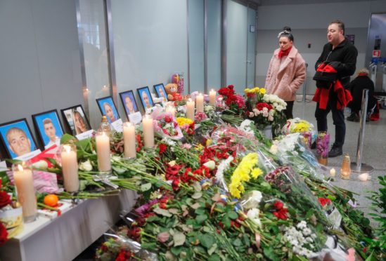 People pay tribute near portraits of crew members of the Ukraine International Airlines Flight PS752 at Boryspil International Airport in Kiev, Ukraine