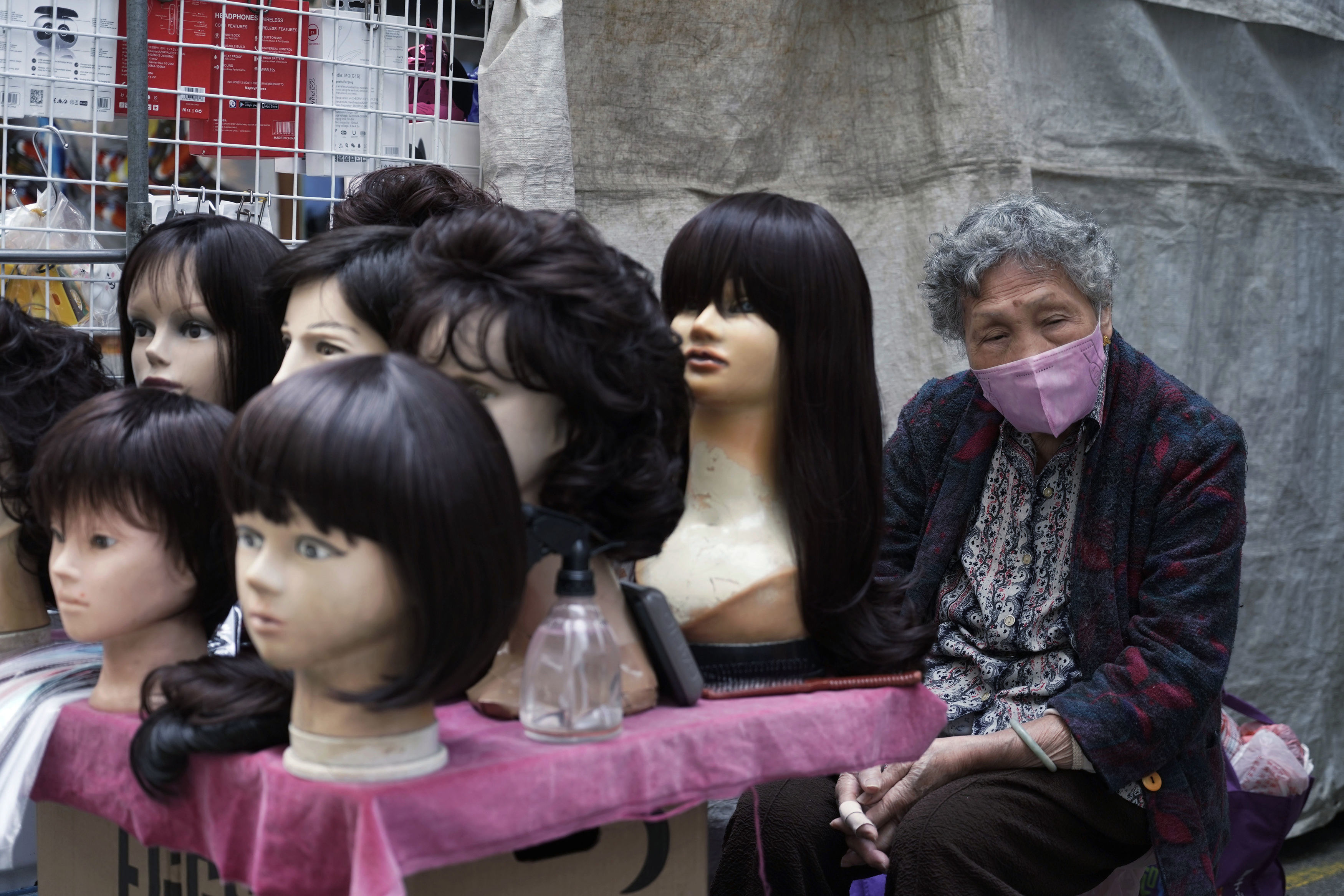 A vendor wears a face mask yesterday at her wig stall in Hong Kong which has blocked travel to China