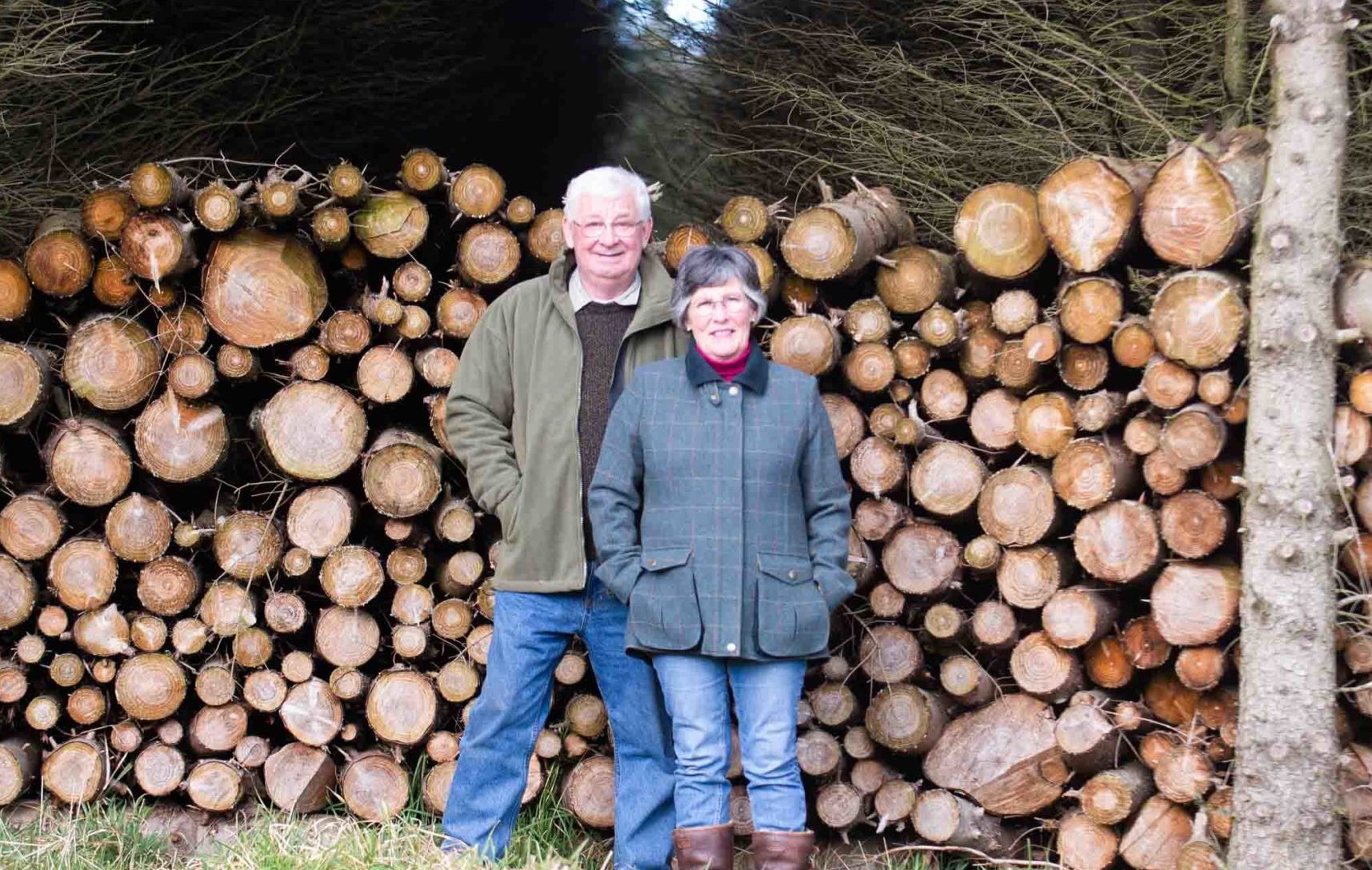 Roger Shipley and Jane Obank with the logs used to power their eco-friendly home