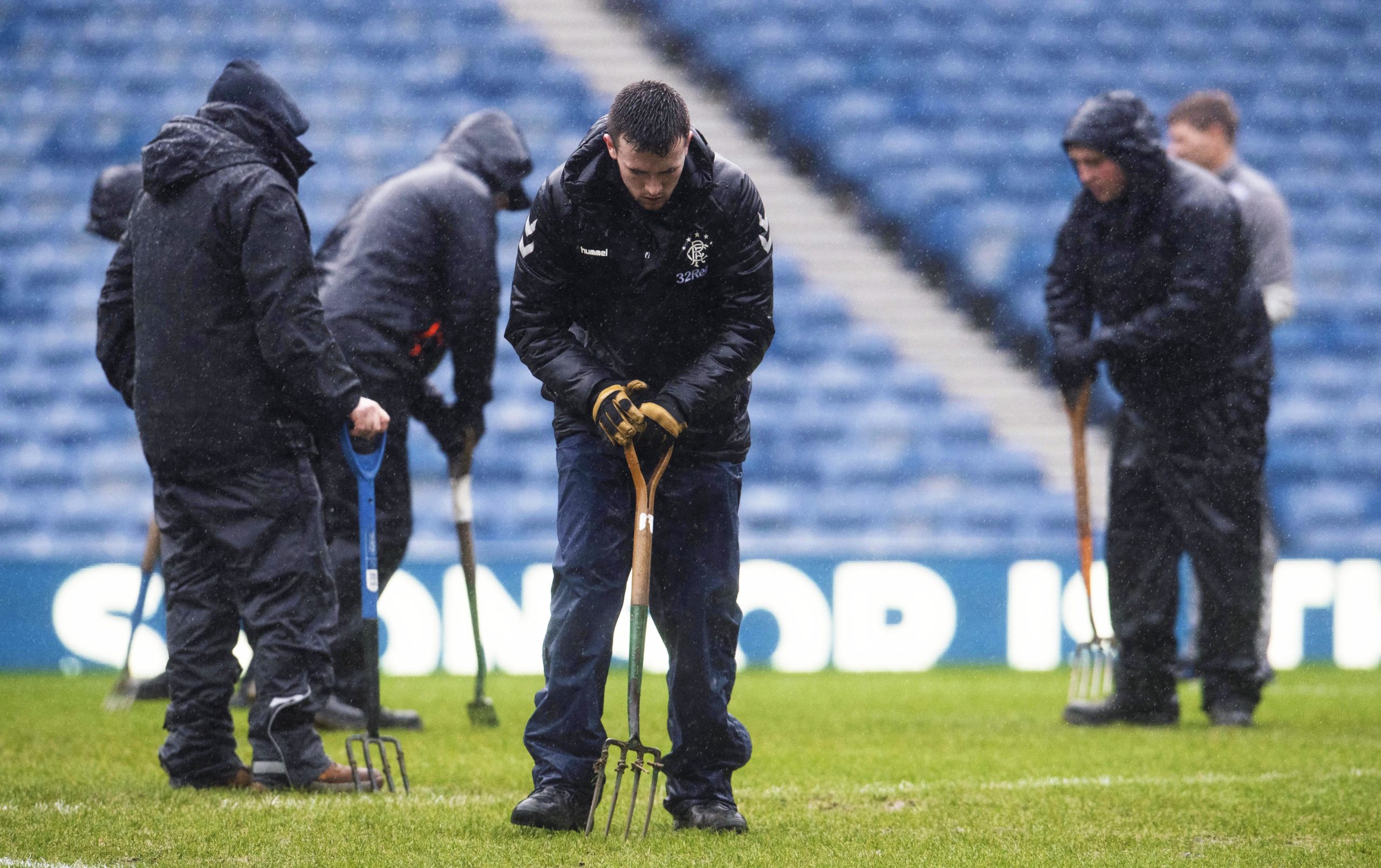 Ground staff tend to the waterlogged Ibrox pitch